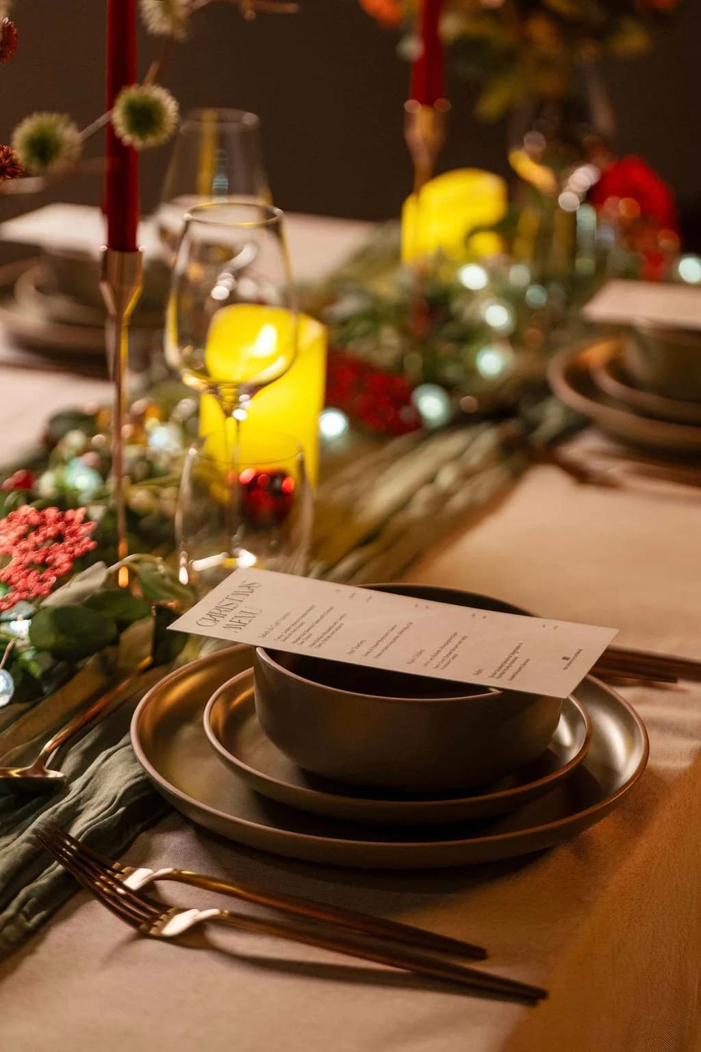 Christmas menu card resting on a bowl at a candlelit place setting