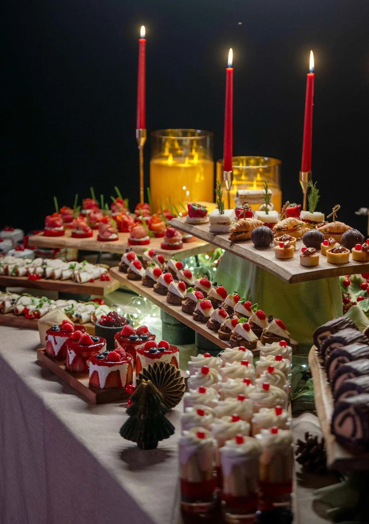 Festive canapé and dessert table lit by red candles